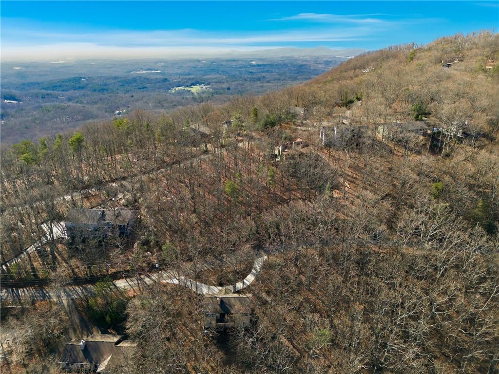 Aerial view of wooded mountain homes and a winding road overlooking a broad valley.