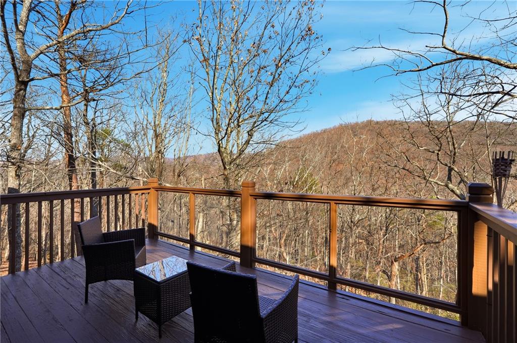 Furnished deck overlooking a wooded mountain hillside.