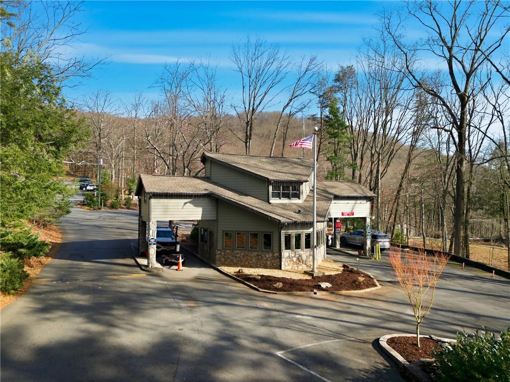 Wooded property entrance with a stone-based building and covered drive-through lanes.