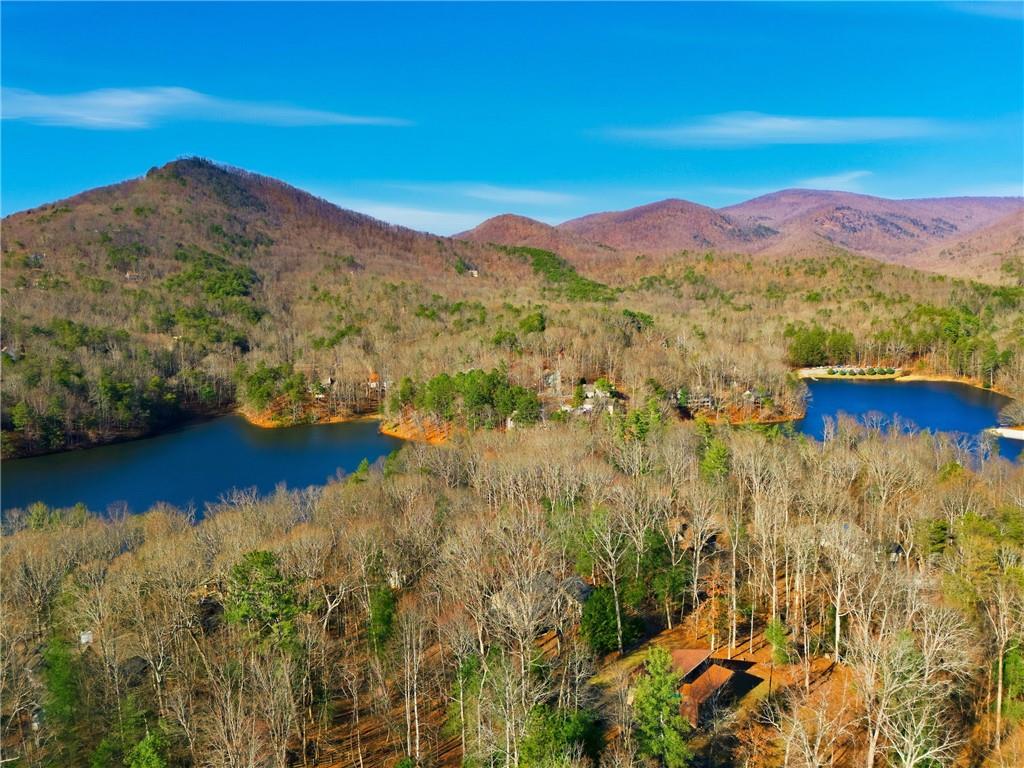 Wooded lakeside property with a blue lake and mountain ridges beyond.