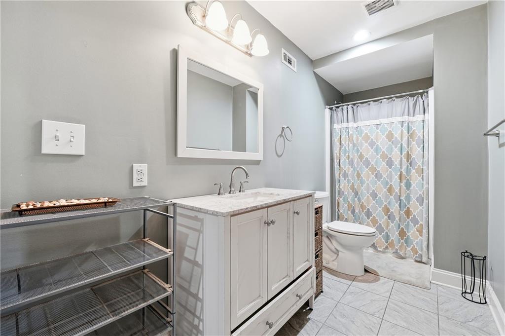 Bathroom with a white vanity, marble-look countertop, and patterned shower curtain.