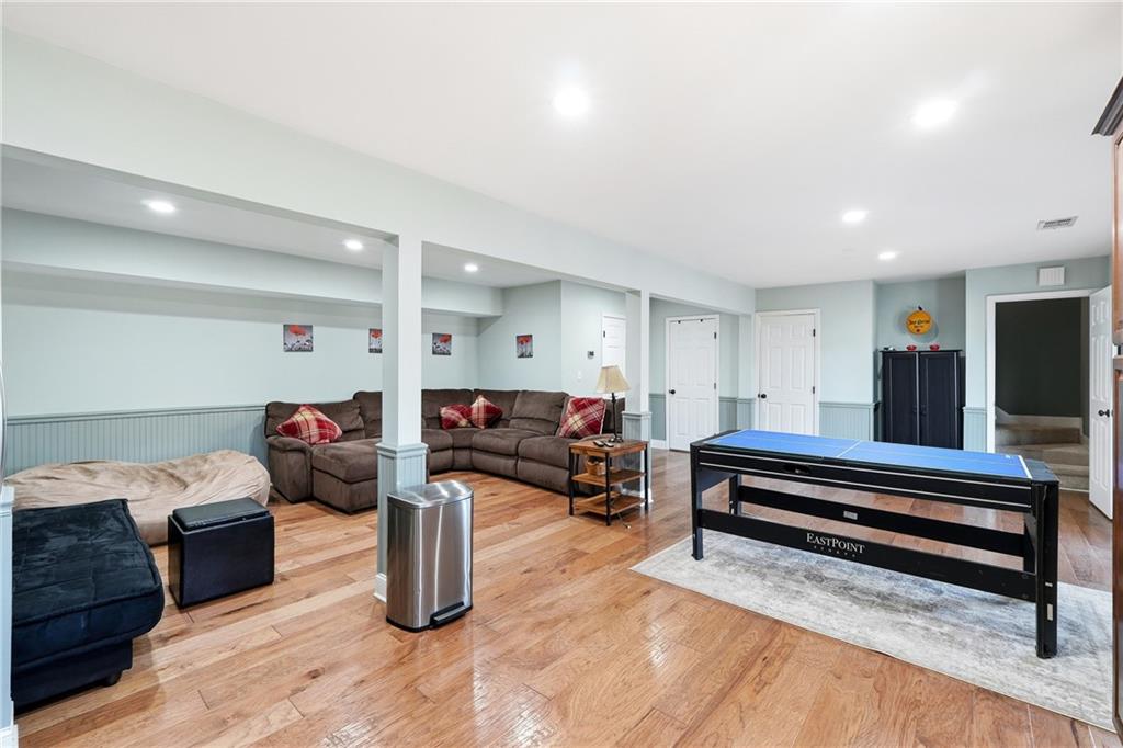 Game room with a blue-felt pool table, brown sectional, and hardwood floors.