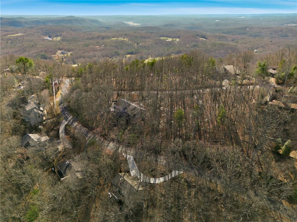 Aerial view of wooded homes and winding roads with distant mountain ridges.
