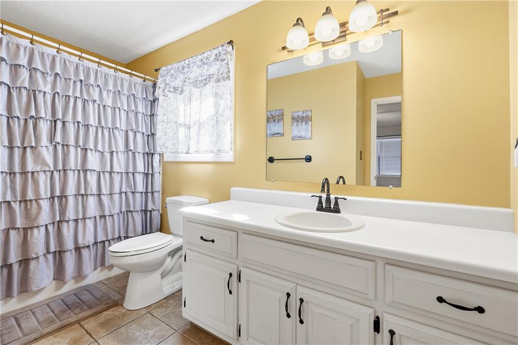 Bathroom with a long white vanity, large mirror, and gray ruffled shower curtain.