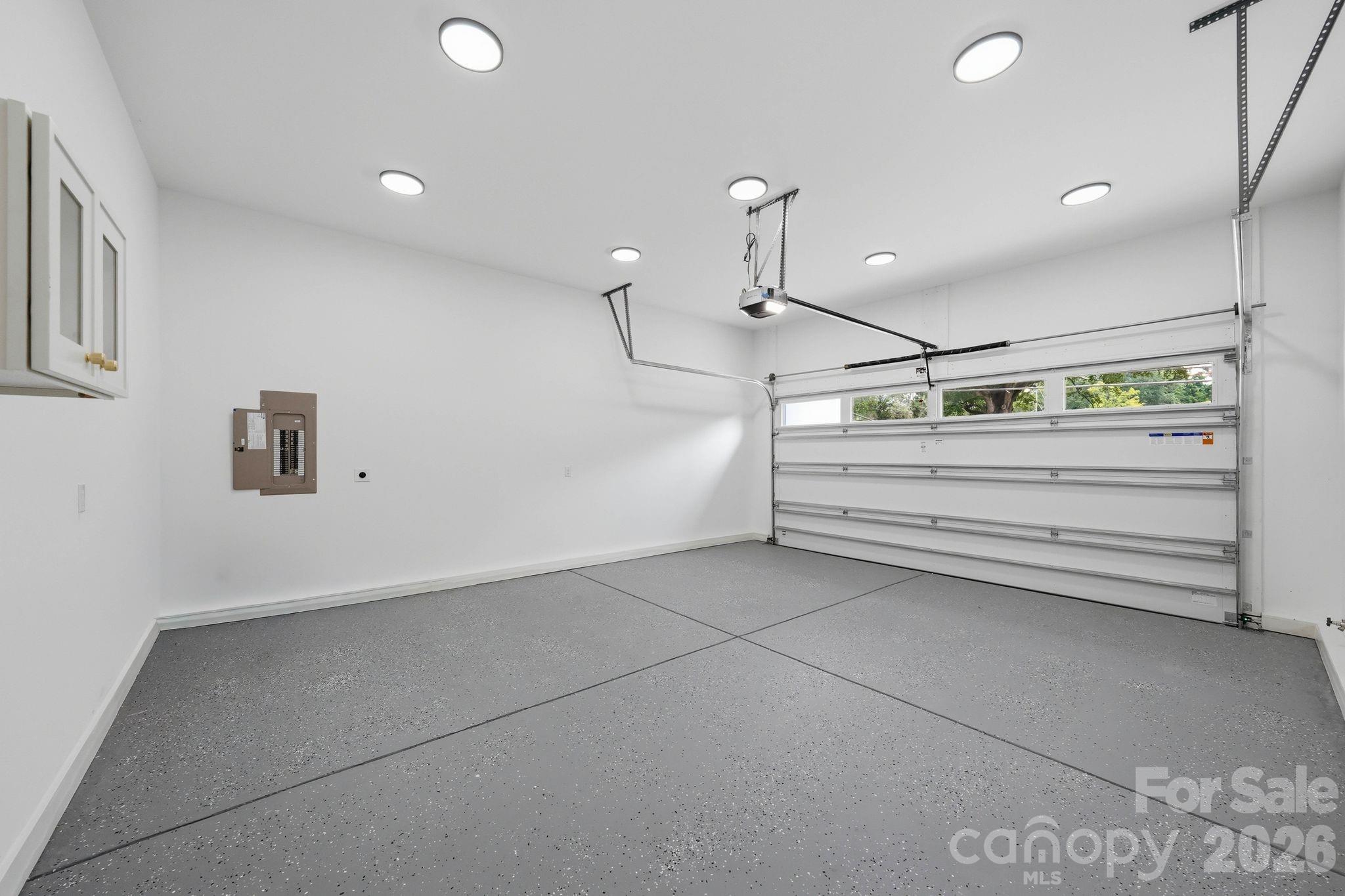 Empty garage with a speckled gray floor and closed sectional door with windows.