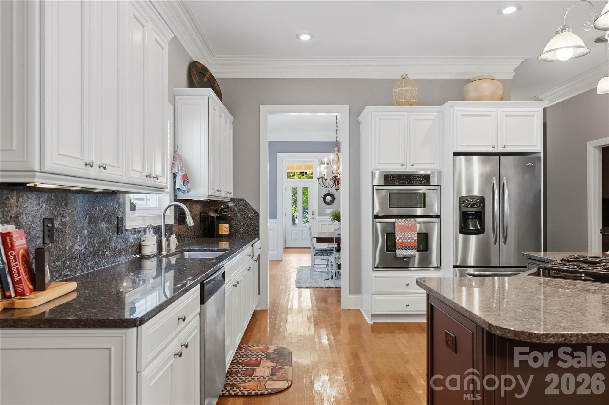 Kitchen with white cabinets, dark granite counters, stainless steel appliances, and a large island.