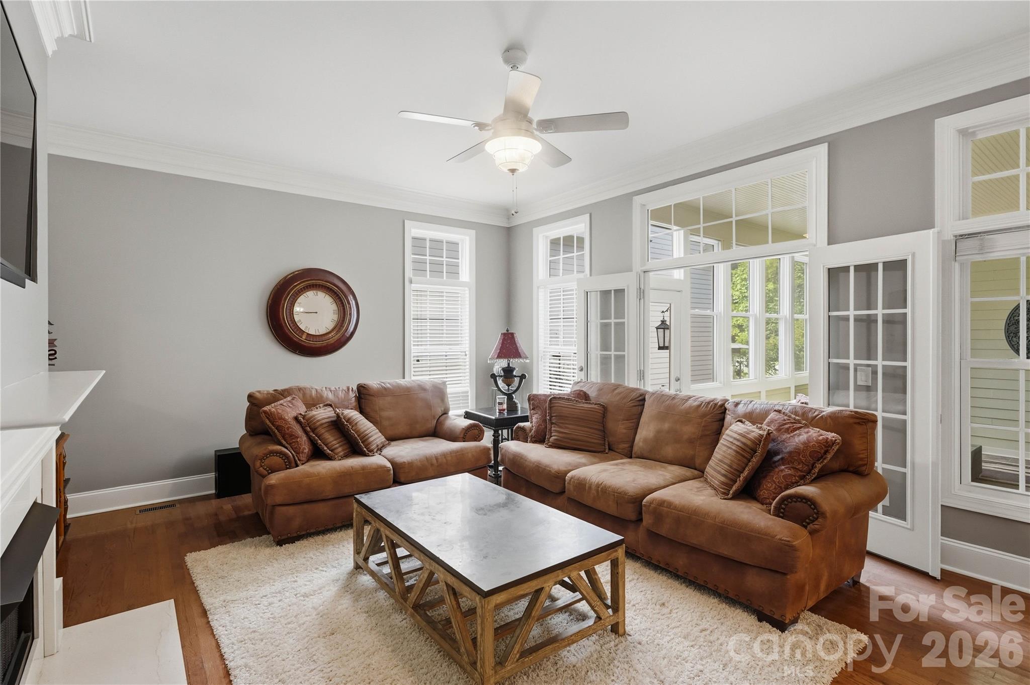 Living room with brown leather sofas, a wood-framed coffee table, and tall windows.