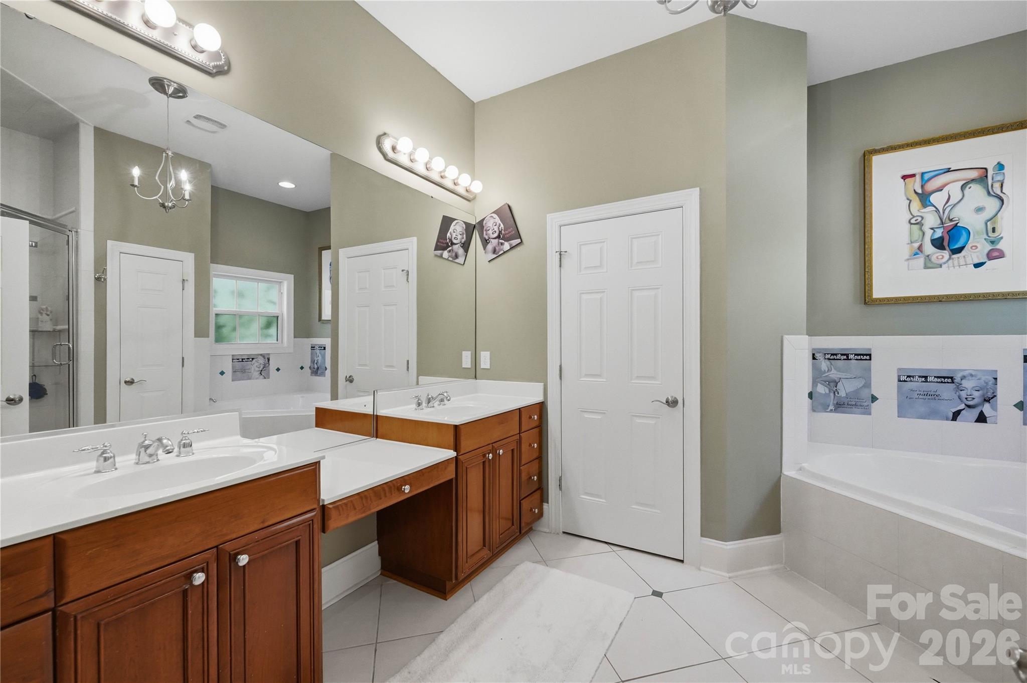 Bathroom with two wood vanities, a large mirror, and a bathtub with decorative Marilyn Monroe tiles.