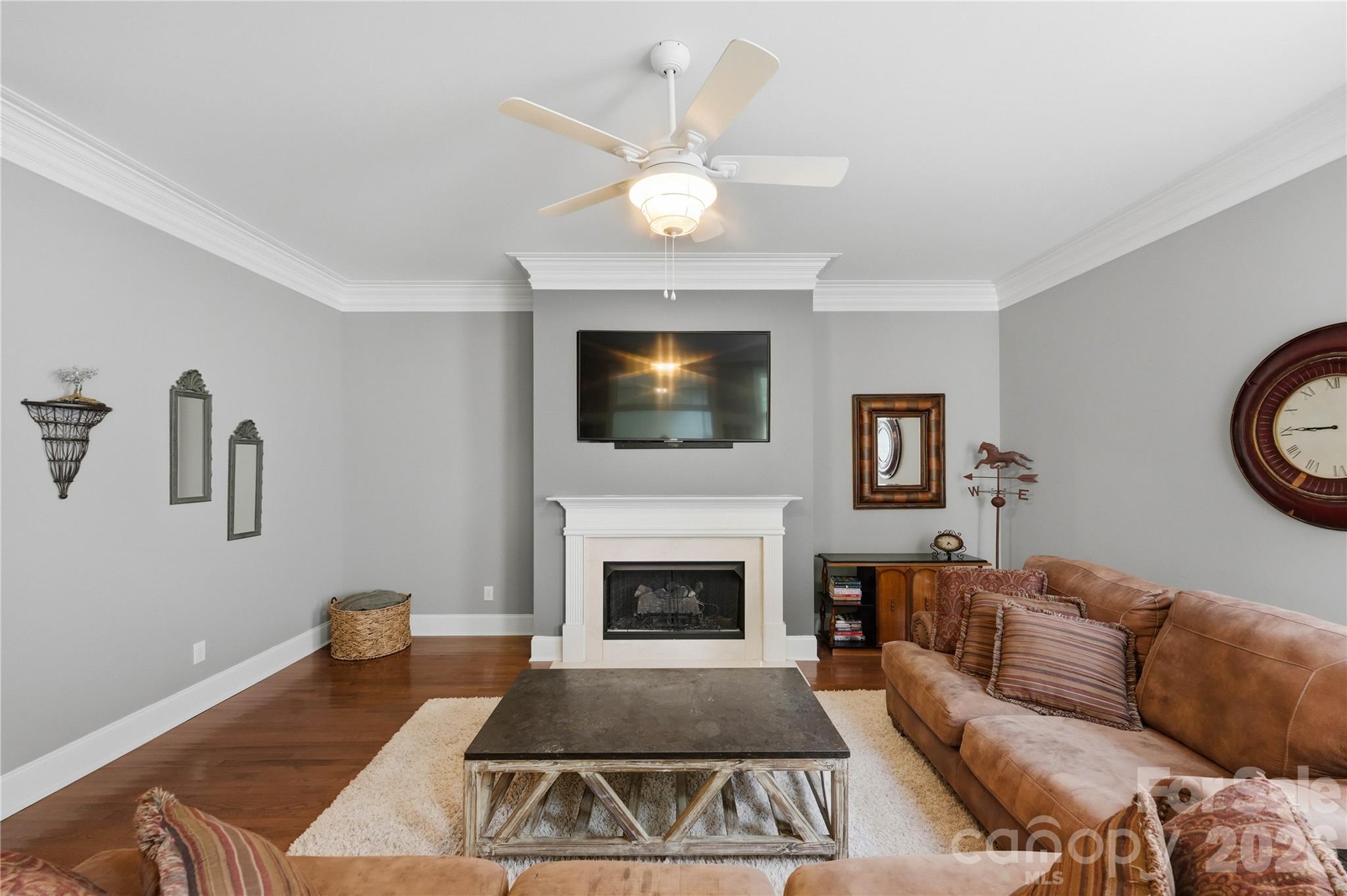 Living room with a white fireplace, wall-mounted TV, and brown sectional sofa.