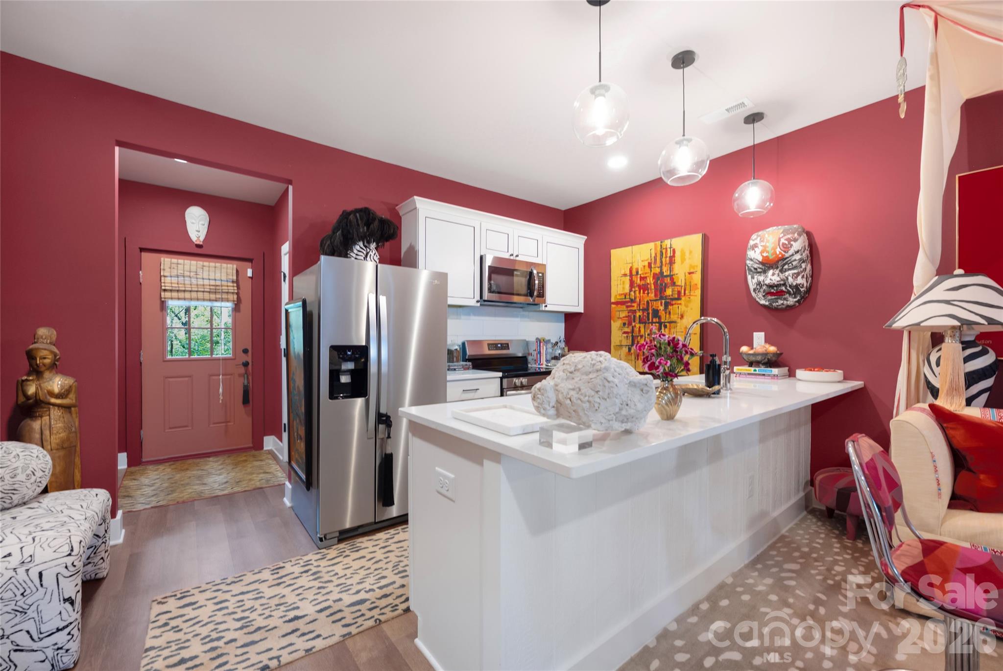 Kitchen with a large white island, stainless steel appliances, and deep red walls.