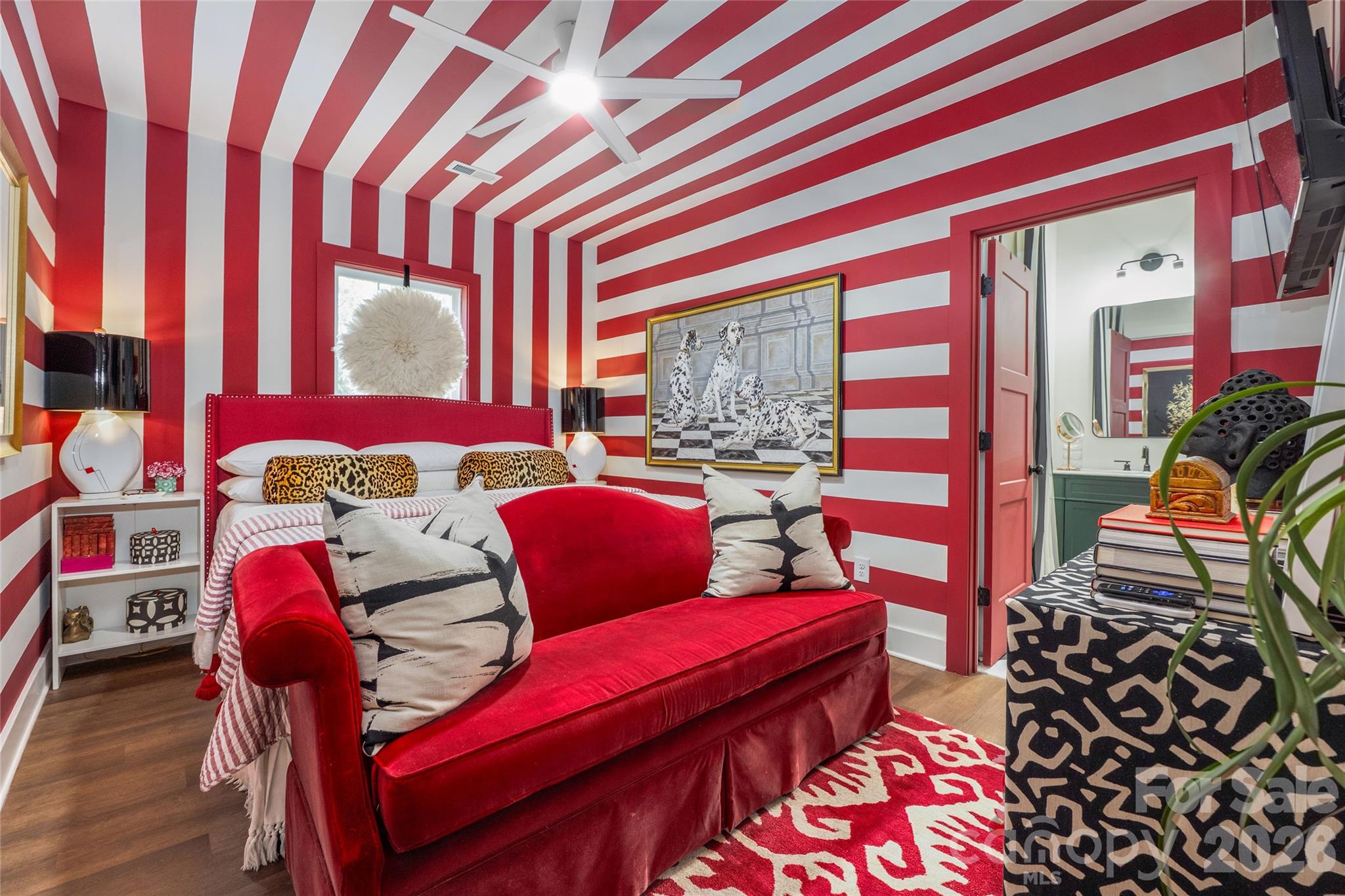 Bedroom with red-and-white striped walls, a red bed, and a velvet sofa.