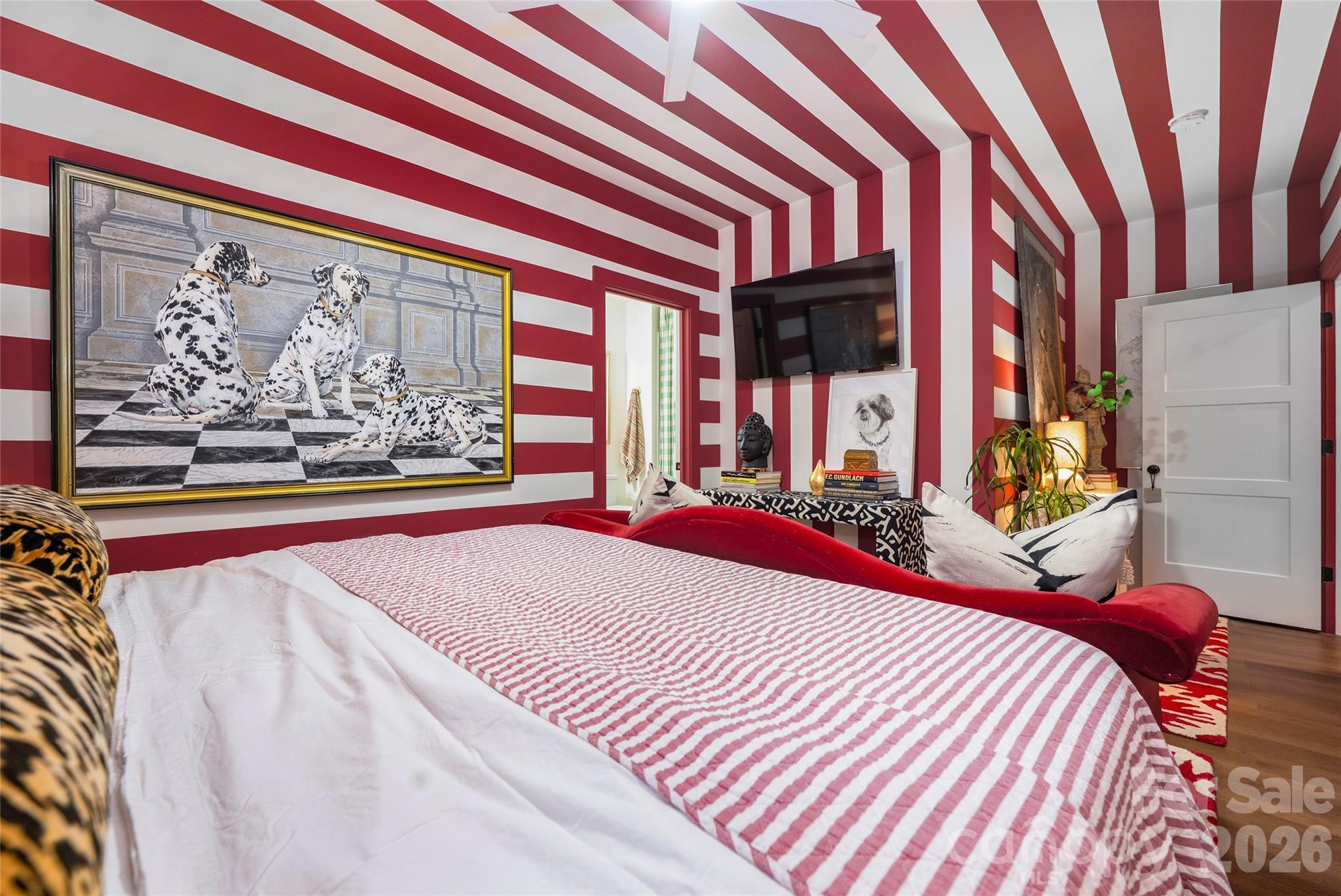 Bedroom with red-and-white striped walls and ceiling, striped bedding, red bench, and Dalmatian artwork.