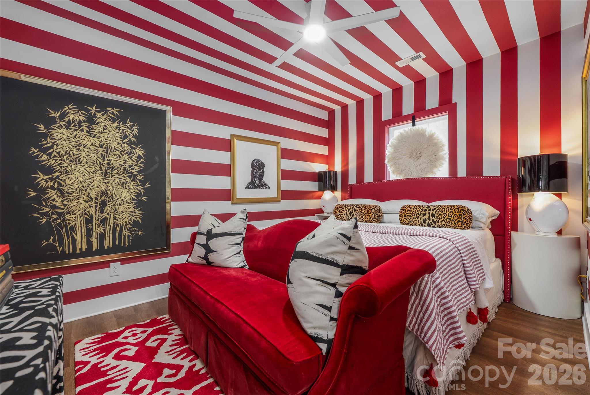 Bedroom with red-and-white striped walls and ceiling, a red bed, and matching sofa.