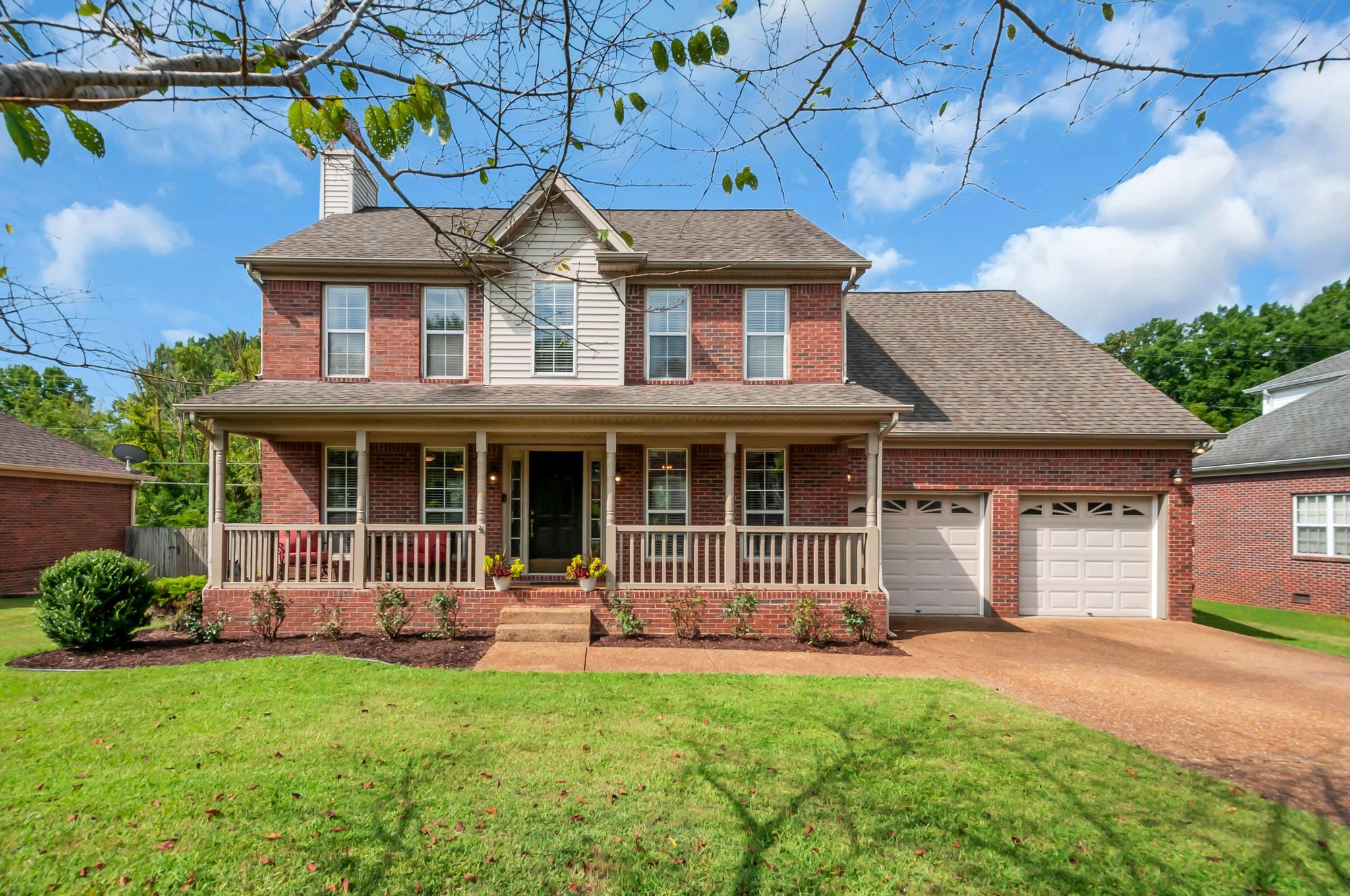Two-story brick house with a covered porch and attached two-car garage.