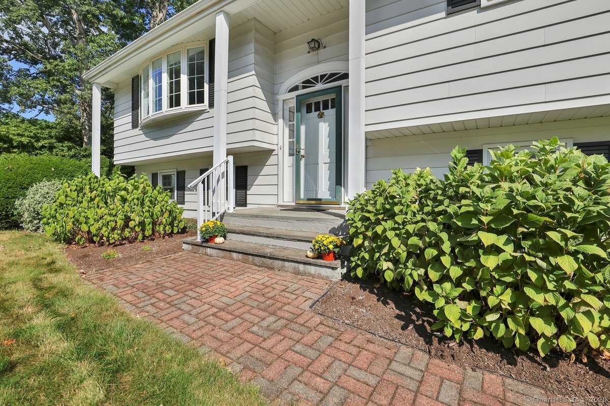 White-sided split-level home with a pale blue front door and brick walkway.