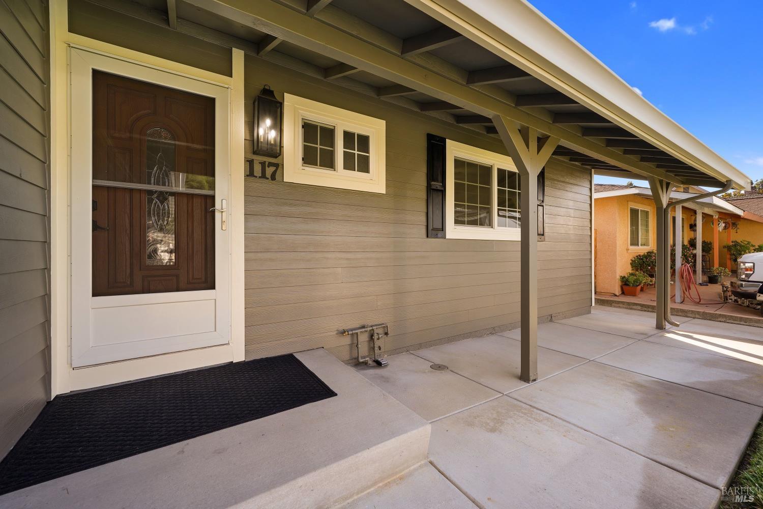 Home entrance with gray siding, dark wood-and-glass door, and a covered concrete entry.