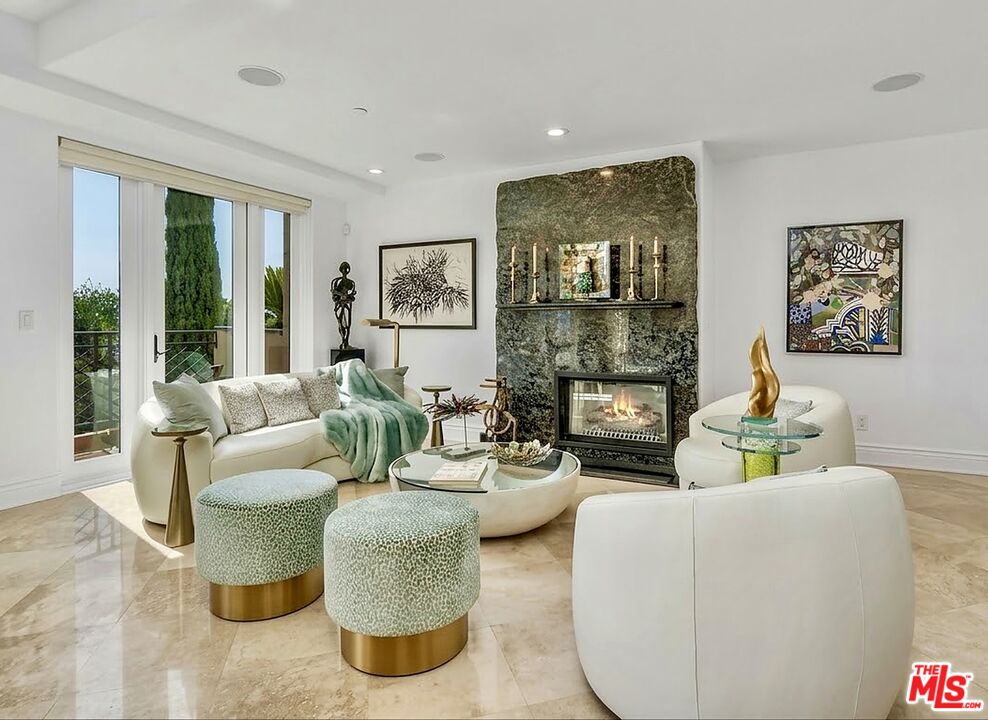 Condo living room with a stone fireplace, curved white seating, and sliding glass doors to a balcony.