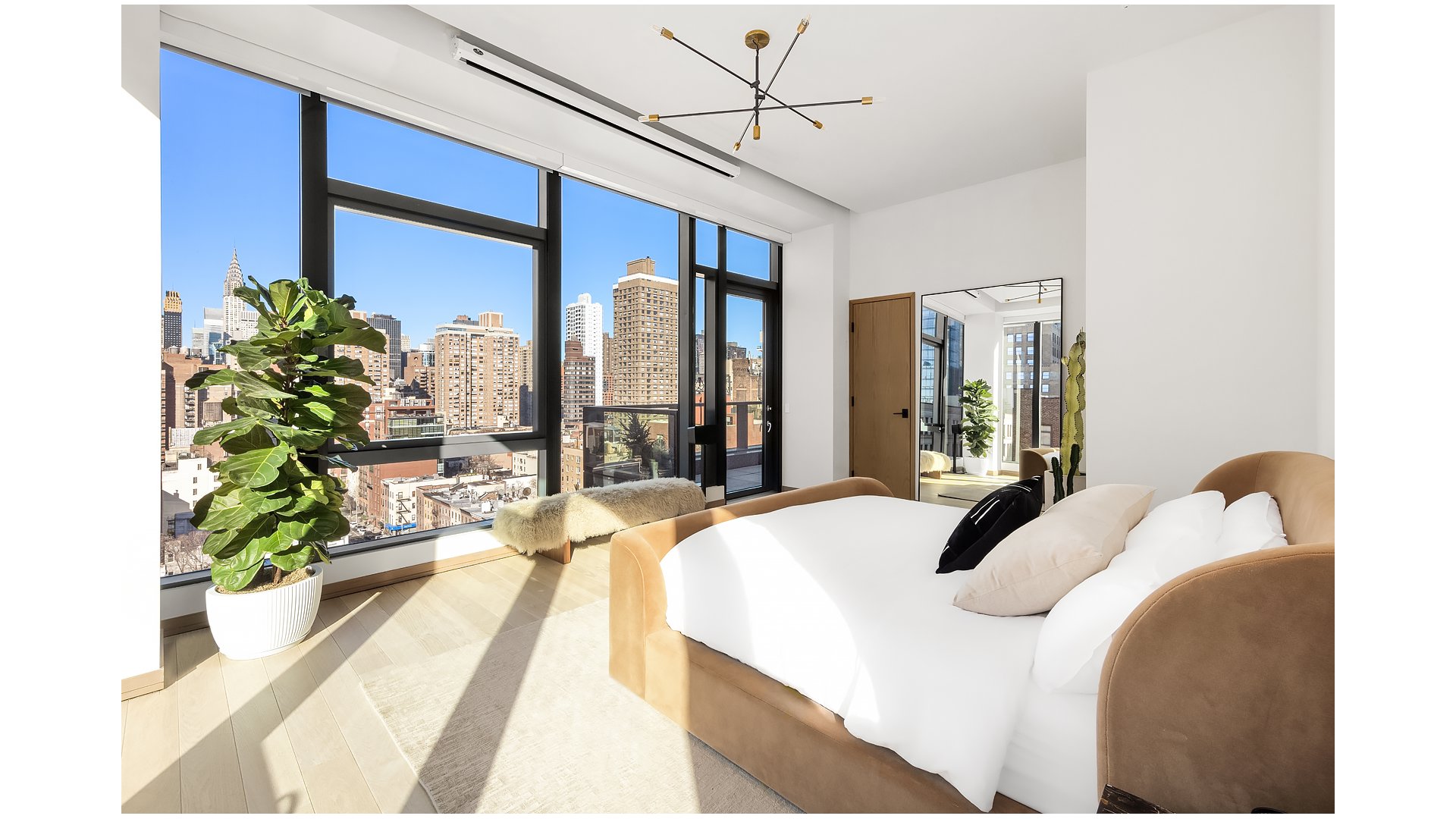 Sunlit bedroom with floor-to-ceiling windows overlooking the Manhattan skyline.