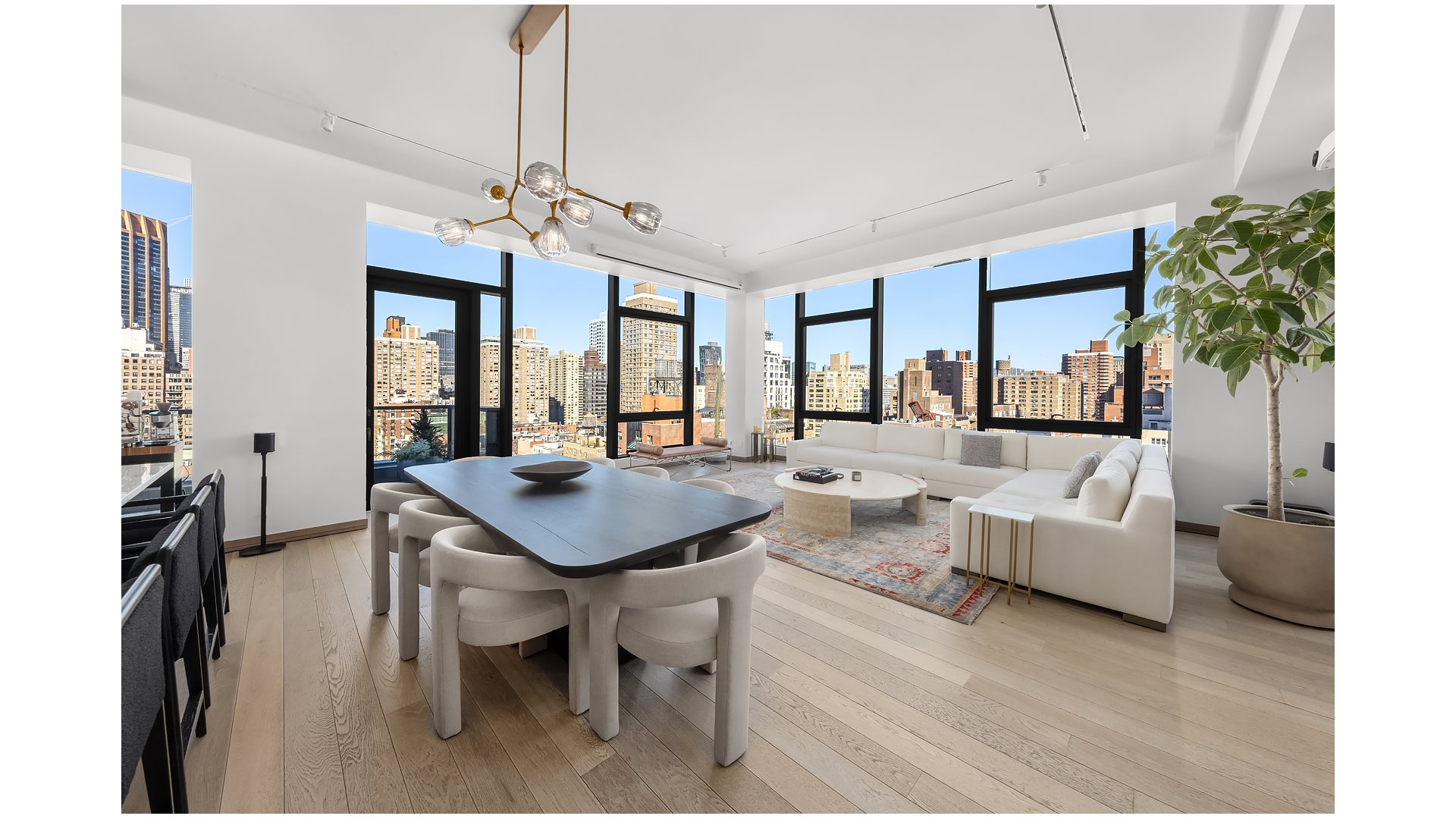 Open-plan living and dining room with floor-to-ceiling windows and city skyline views.