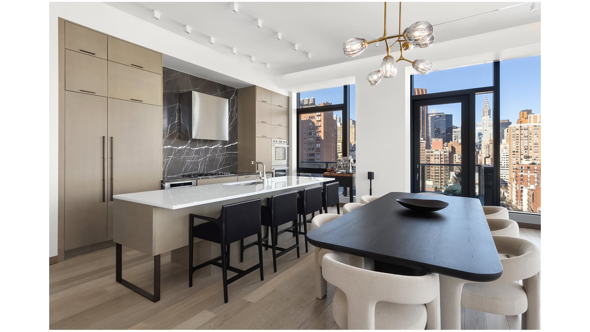 Open-plan kitchen and dining area with a waterfall island and Manhattan skyline views.