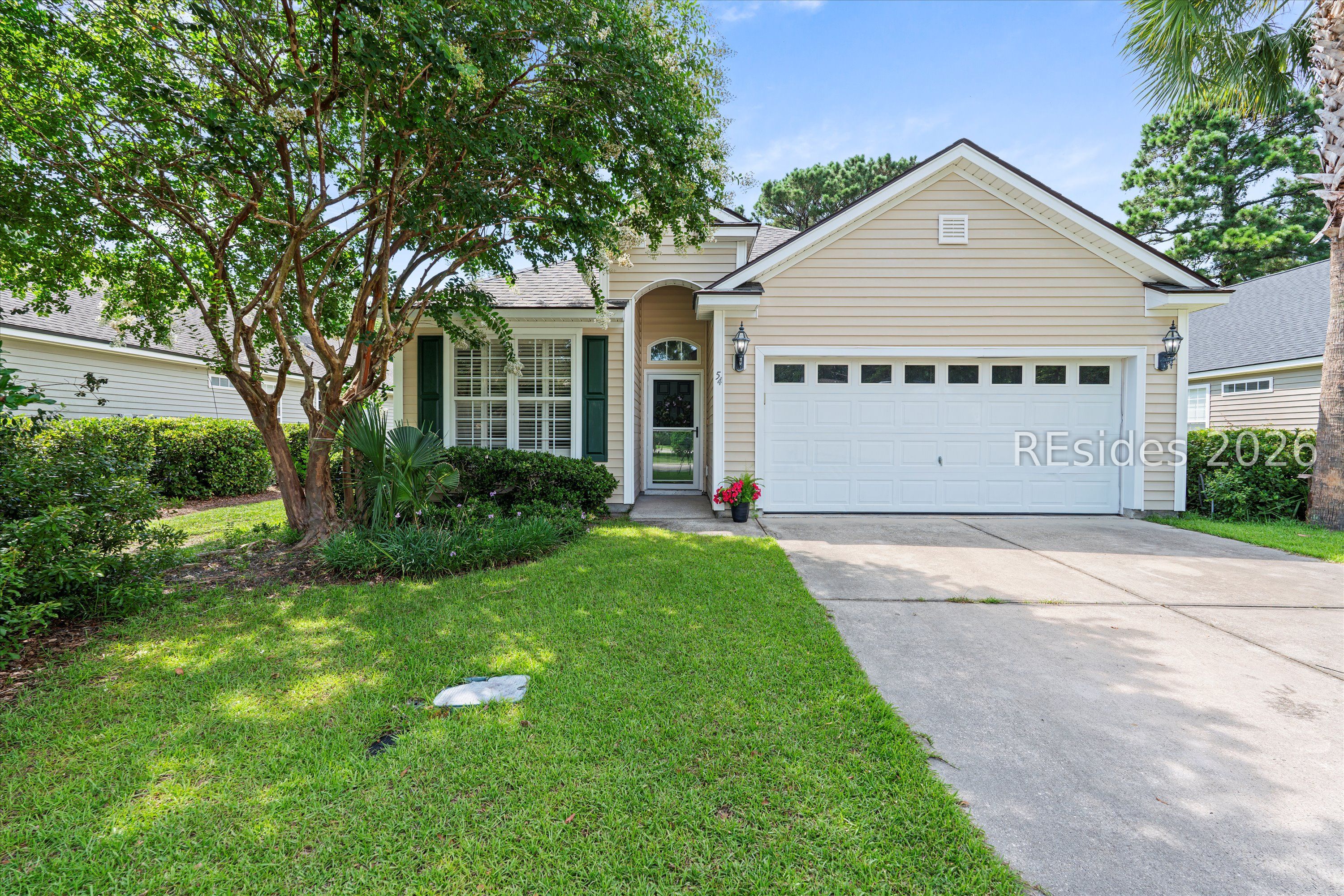 Home at 54 Trotting Hill Lane with beige siding, a white garage, and mature trees.