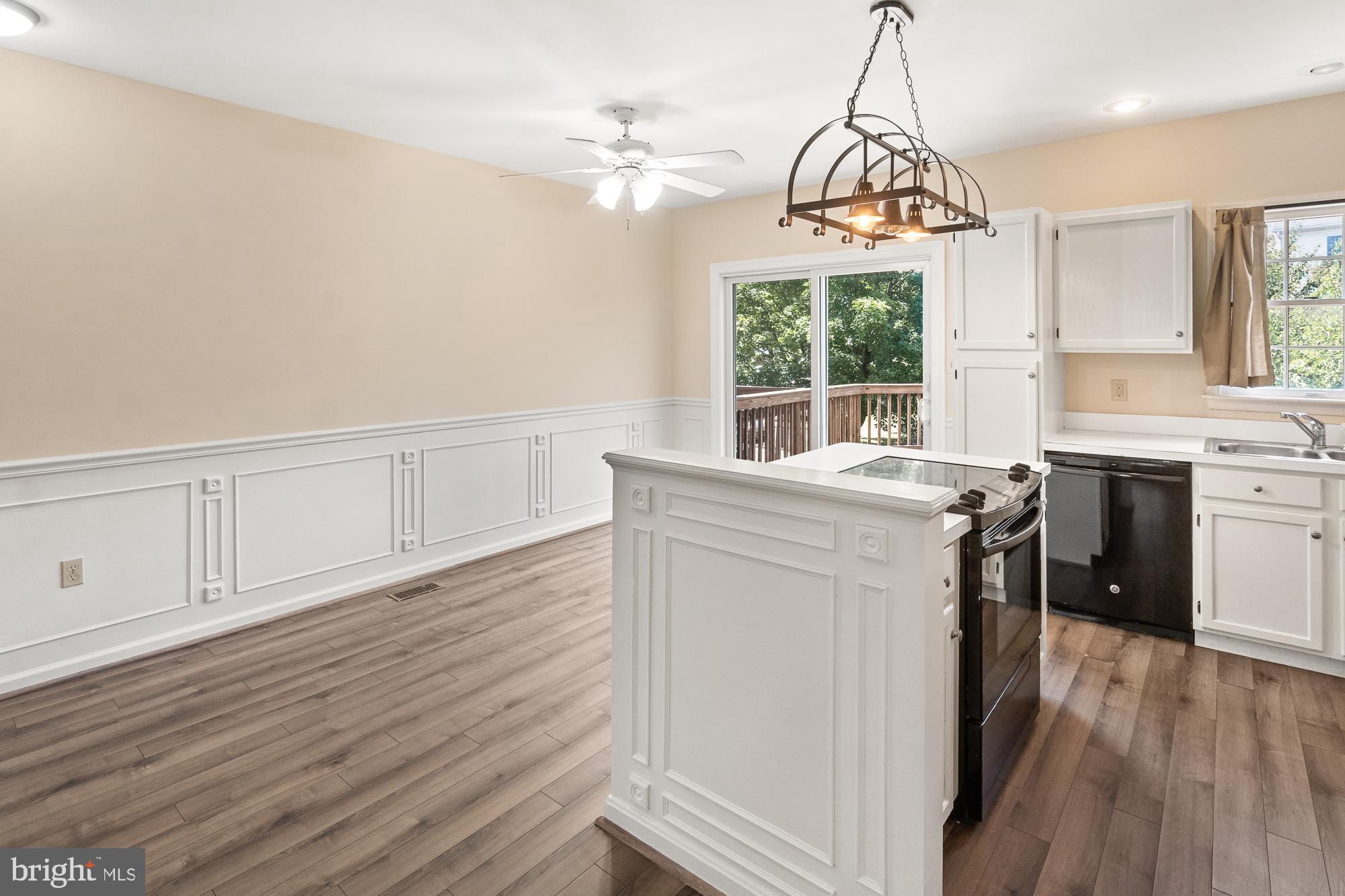 Kitchen with a large white island, black range, wood-look floors, and sliding doors to a deck.