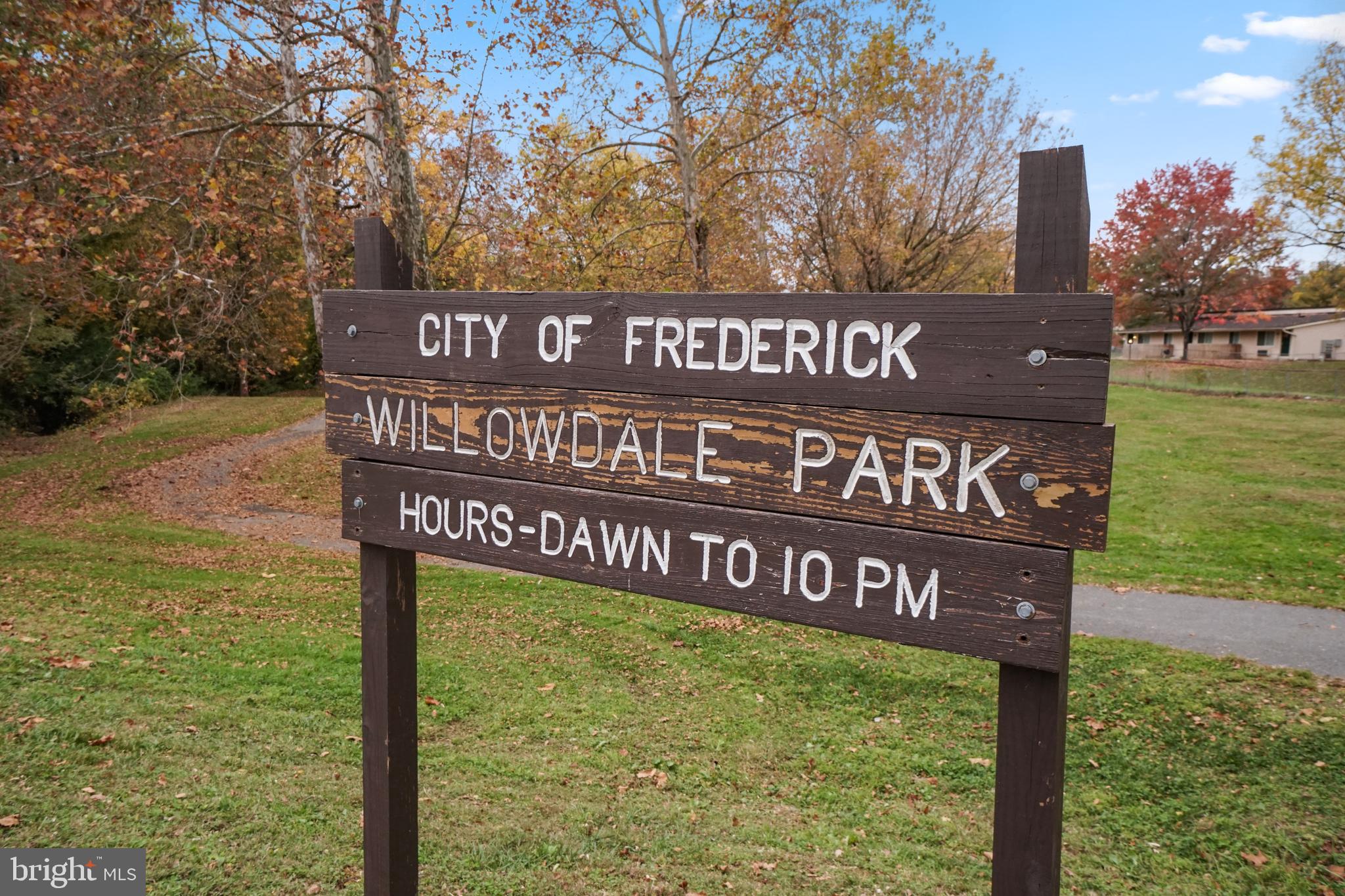 Willowdale Park sign with a walking path and autumn trees.