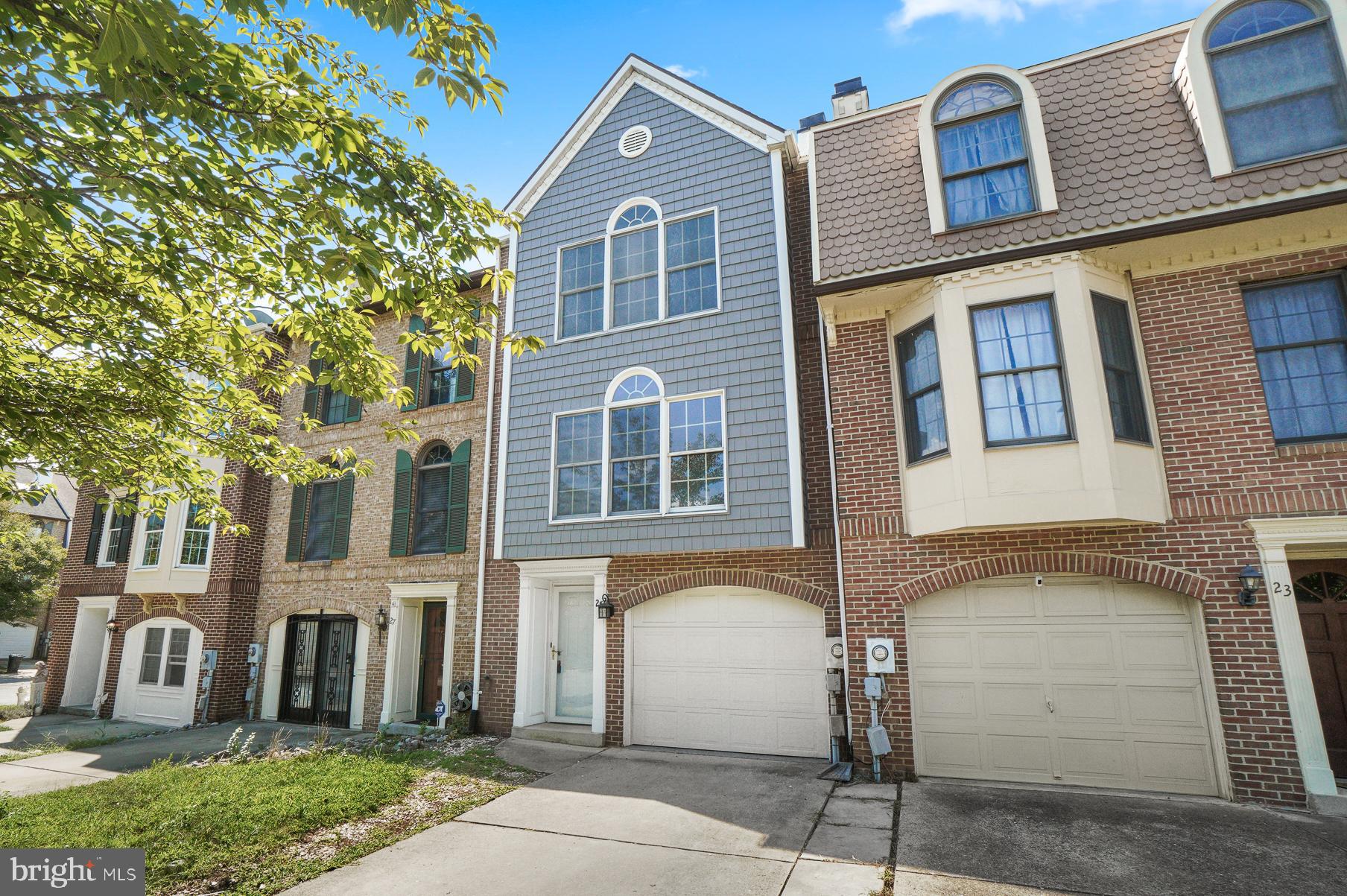 Blue-gray townhouse with white trim, arched windows, and an attached garage.