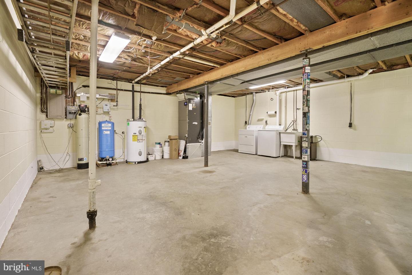 Unfinished basement with exposed ceiling joists, utility equipment, and a washer and dryer.