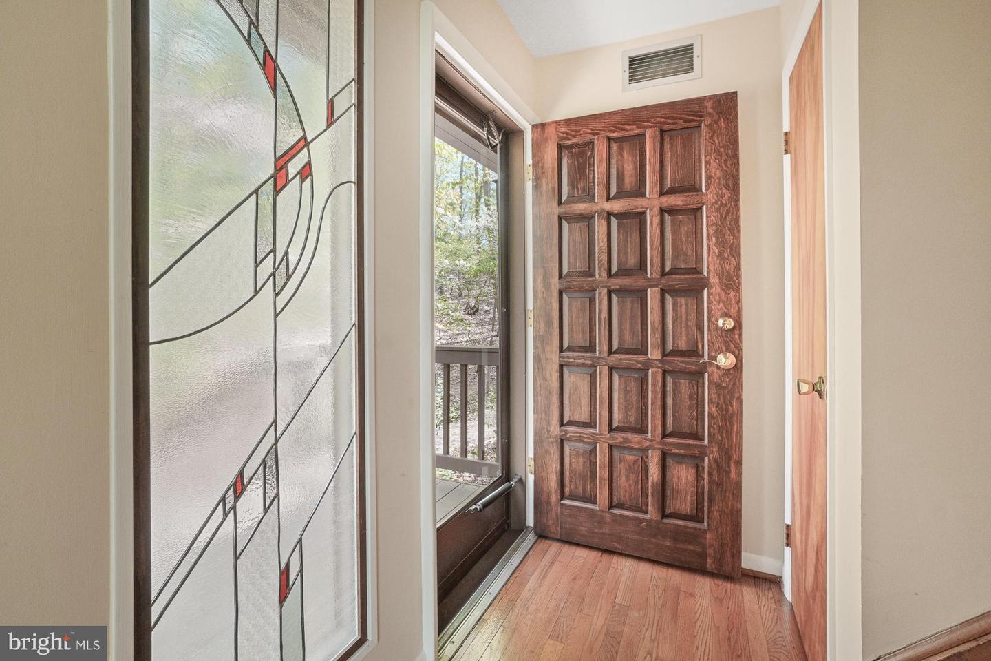 Entryway with a paneled wood front door, stained-glass sidelight, and hardwood floors.