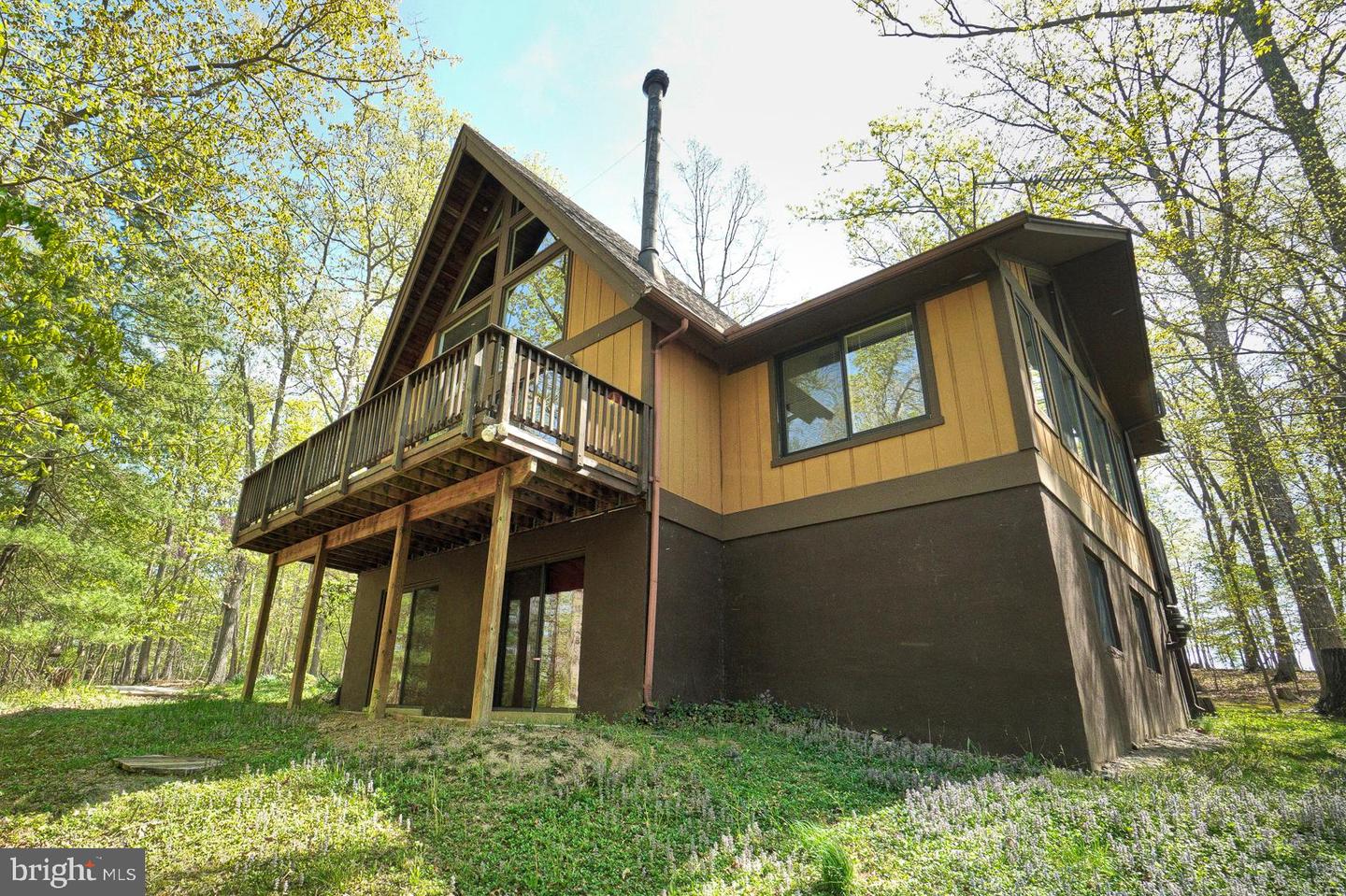Two-story wooded home with an elevated wooden deck and tall gabled roof.
