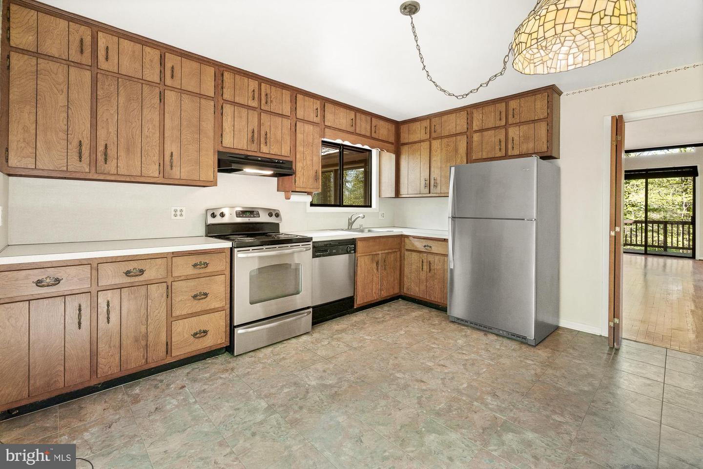 Kitchen with extensive wood cabinetry, stainless-steel appliances, and a doorway to a wooded deck.