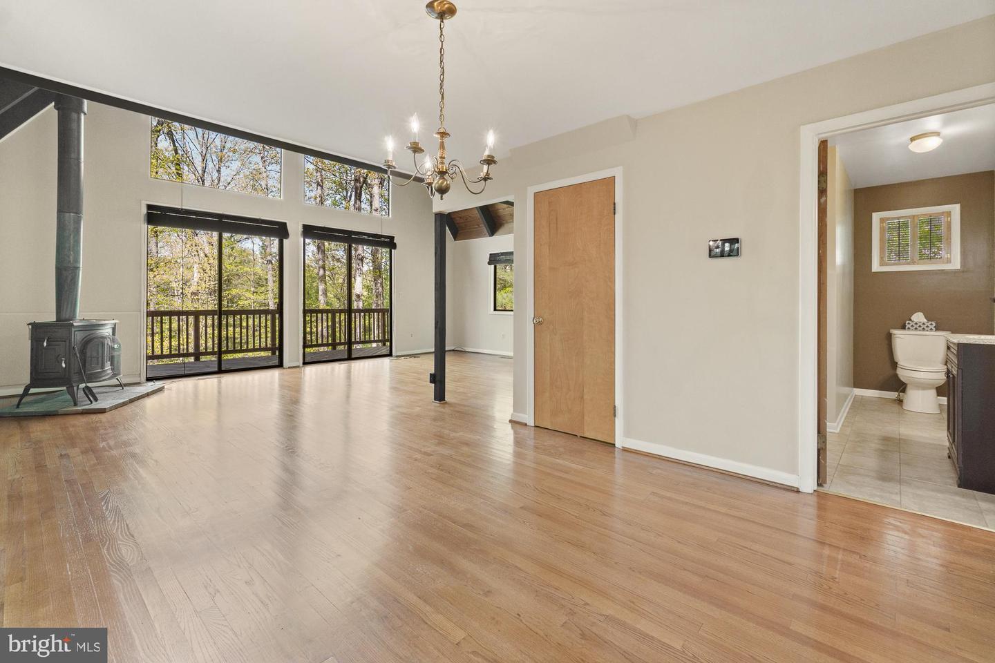 Living room with hardwood floors, a wood stove, and sliding doors overlooking trees.
