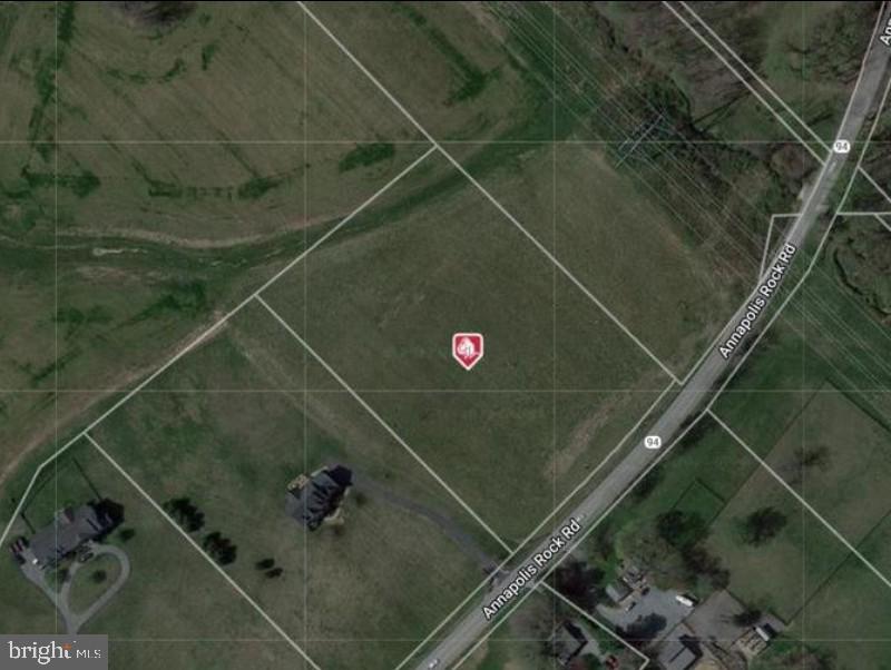 Aerial view of a grassy parcel outlined beside Annapolis Rock Road, with a red property marker.