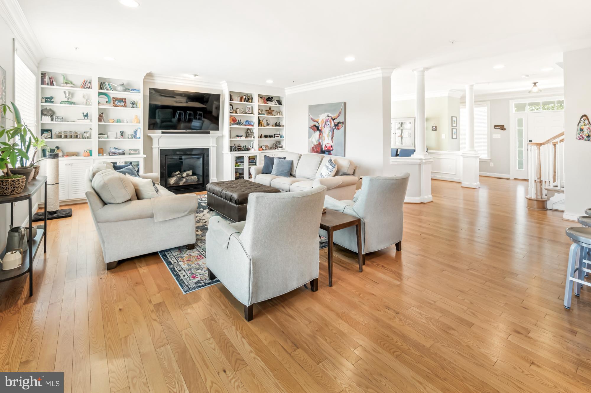 Furnished living room with built-in shelves, a fireplace, and hardwood floors.
