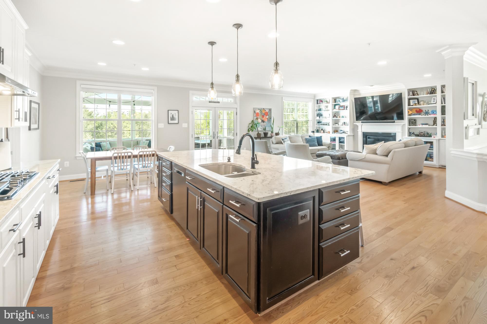 Open-plan kitchen with a large dark island and pale stone countertop beside a furnished living room.