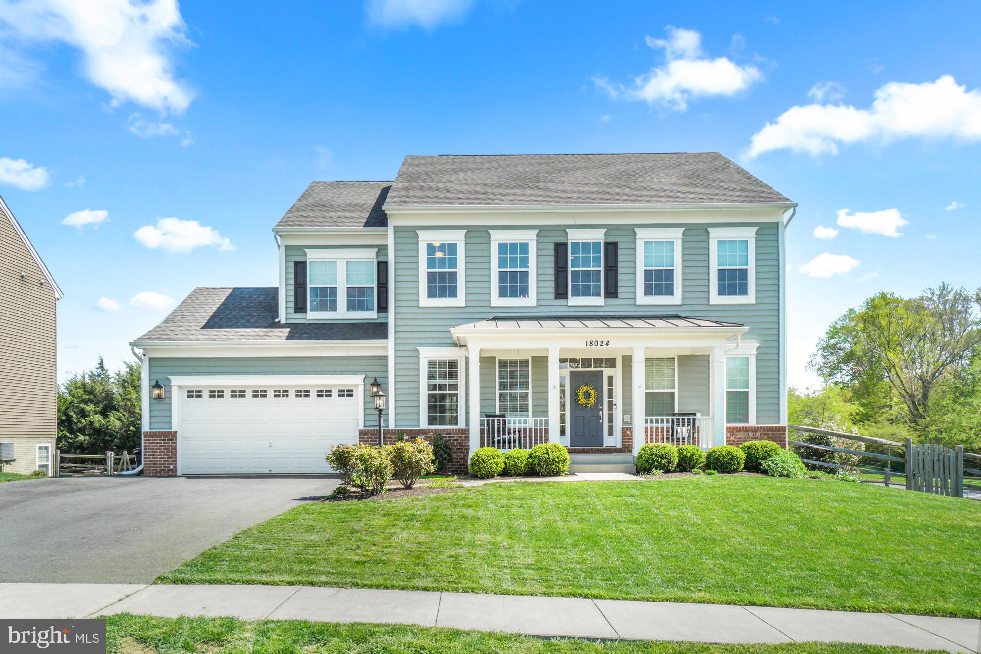 Blue-gray two-story house with white trim, a two-car garage, and a covered front porch.