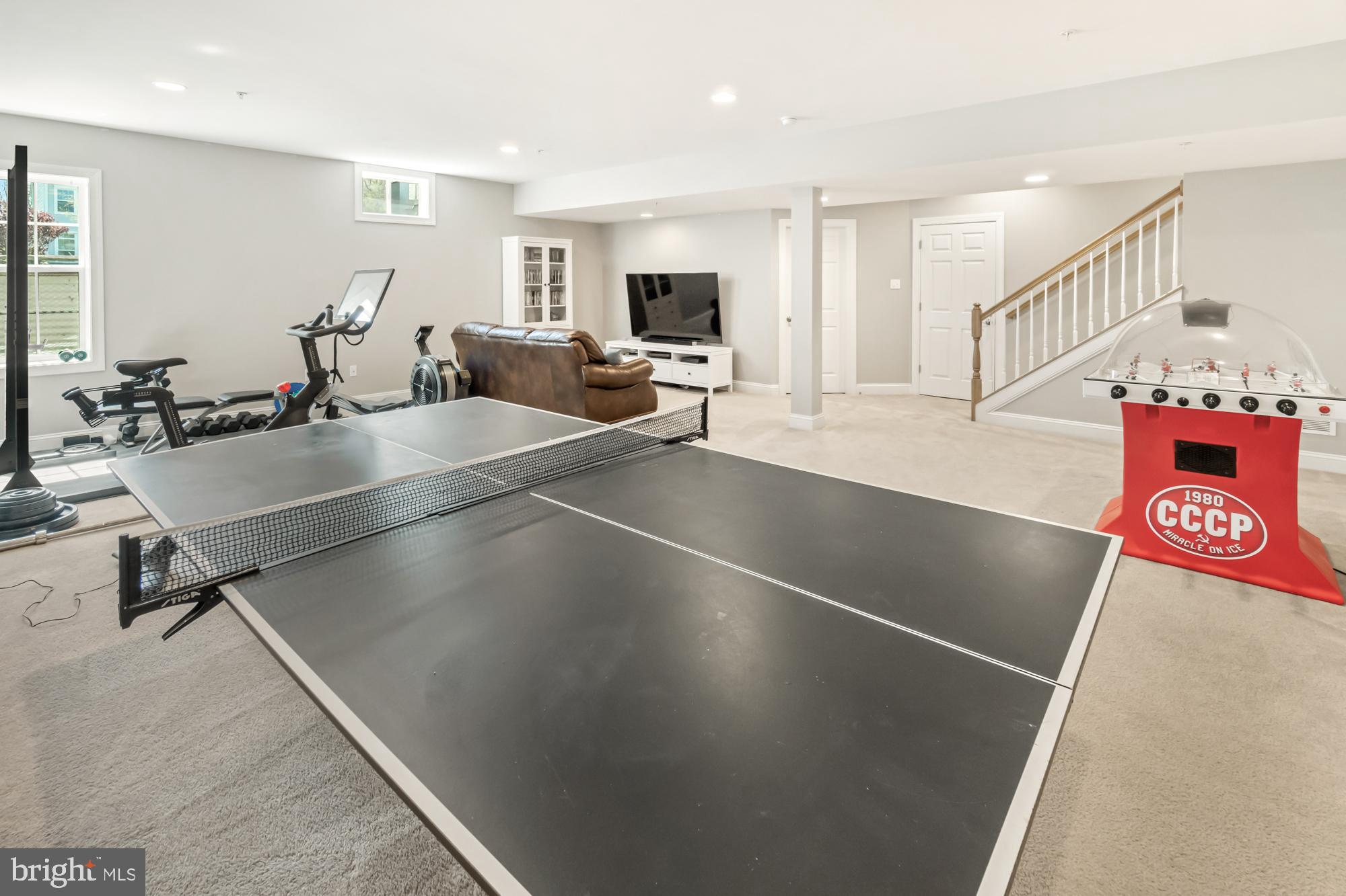 Basement recreation room with a ping-pong table, exercise equipment, and tabletop hockey game.