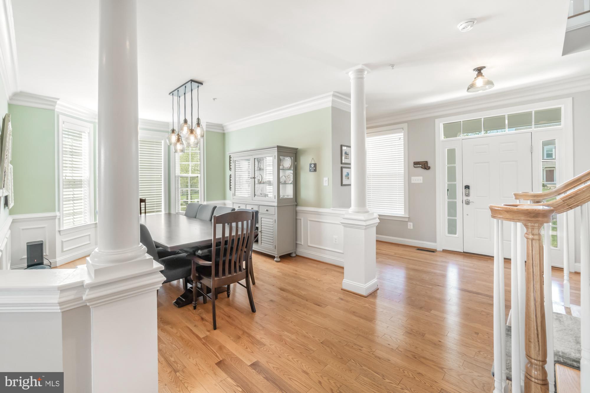 Dining room and entryway with hardwood floors, white columns, and a glass-front china cabinet.