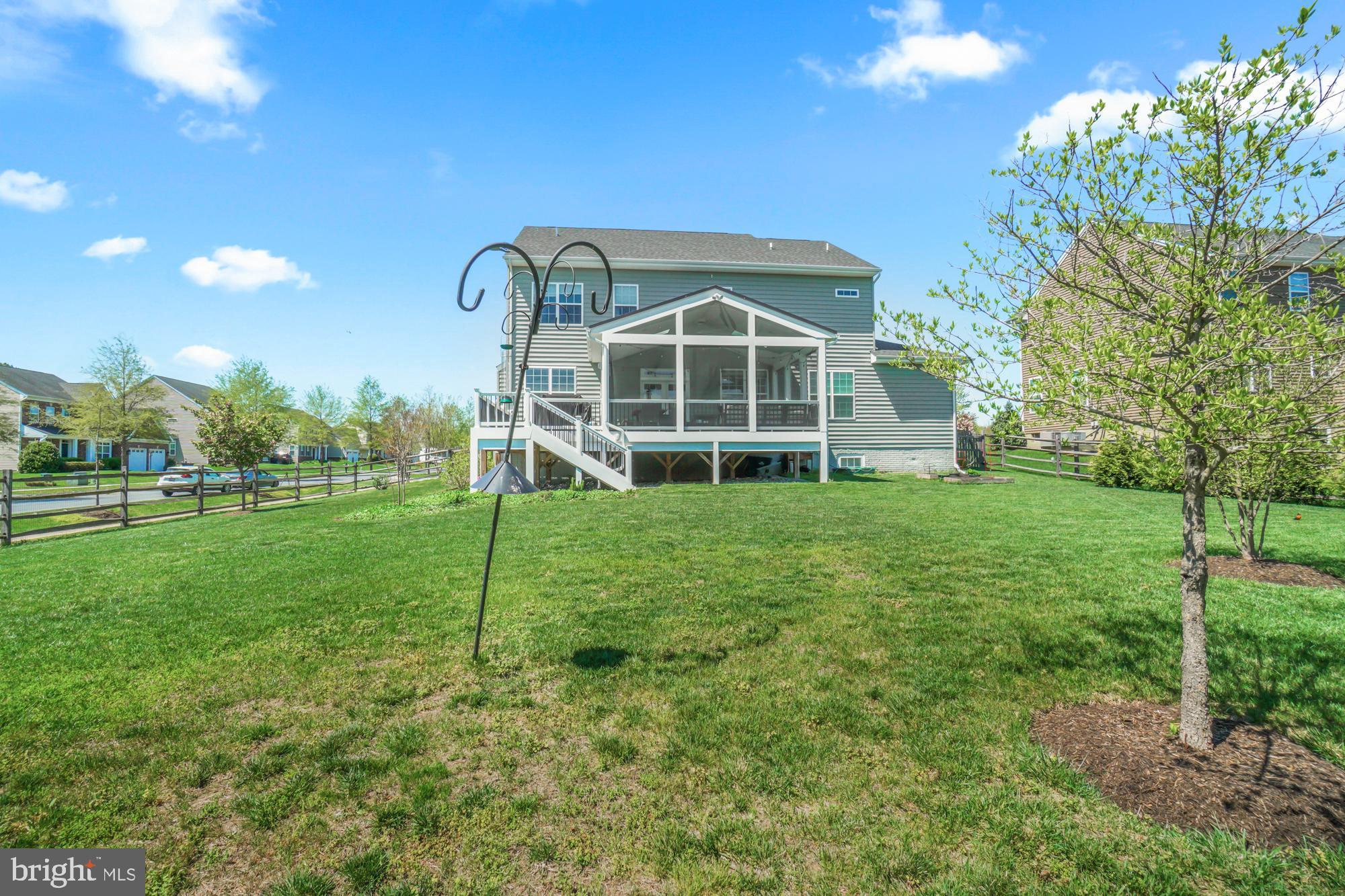 Rear of a gray two-story home with a large screened porch overlooking a spacious grassy backyard.