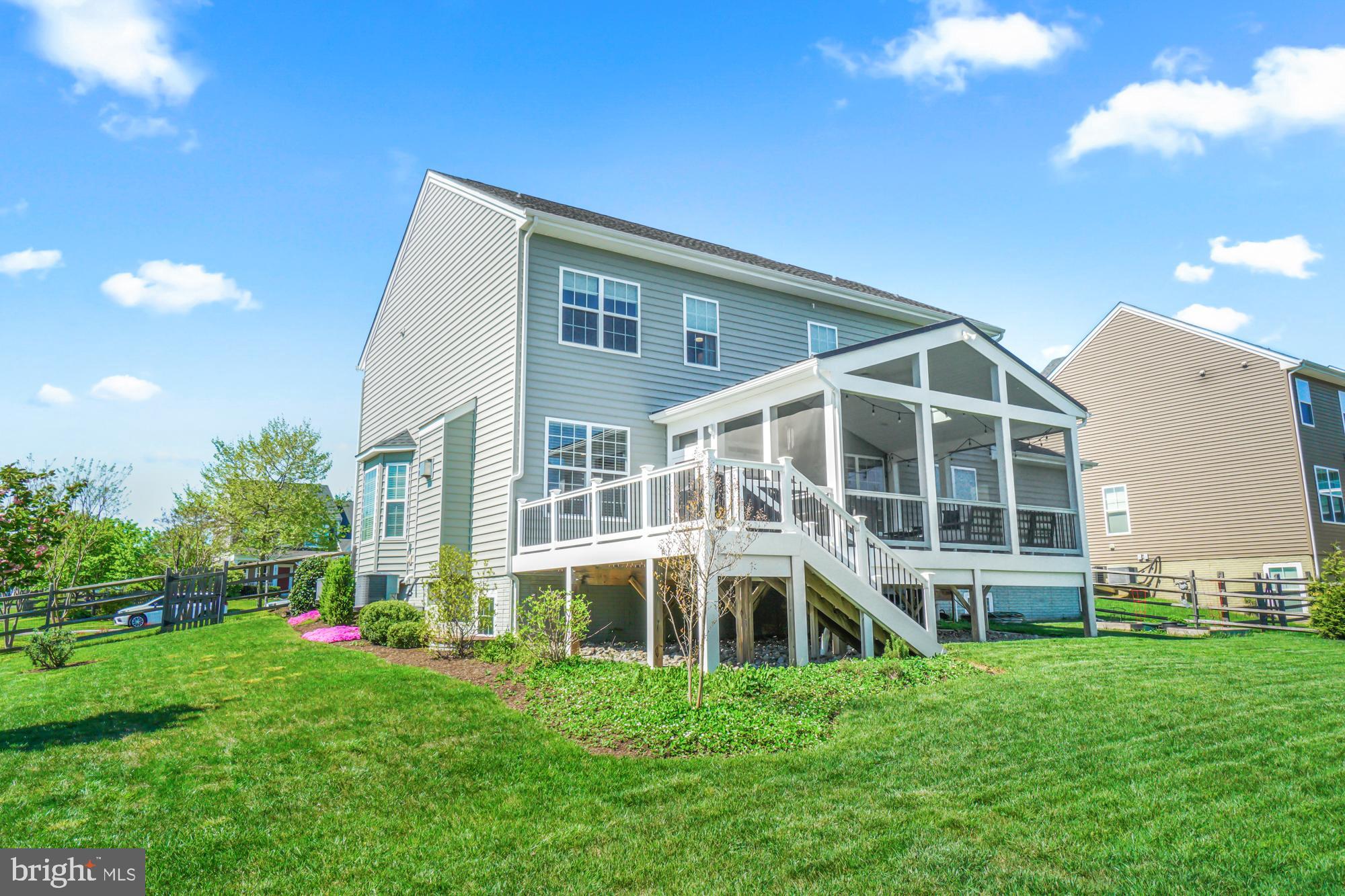 Rear exterior of a two-story gray home with a raised deck and screened porch.