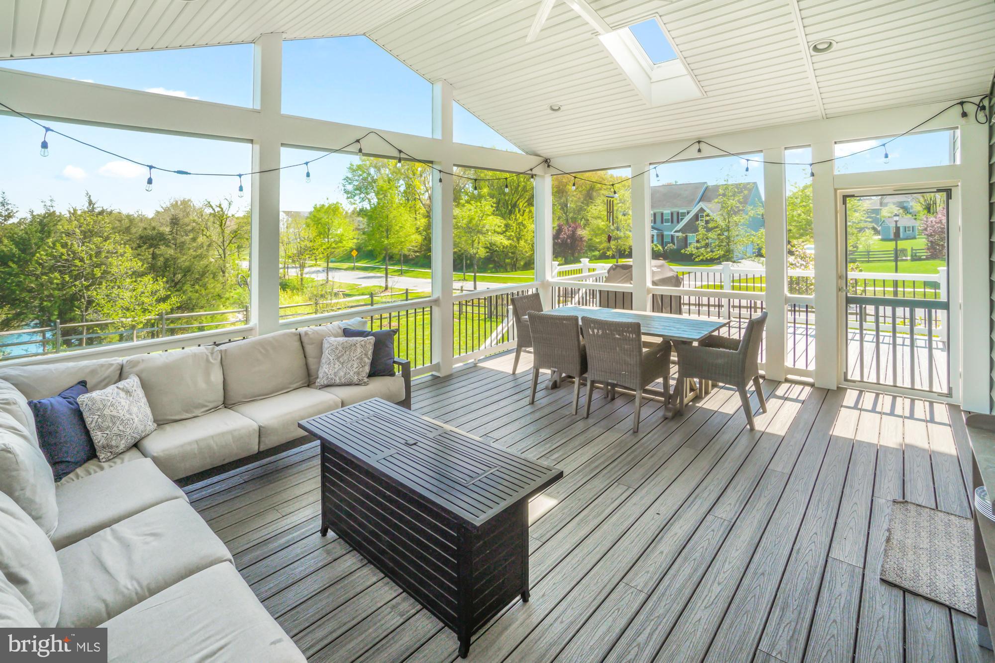 Covered porch with a skylight, string lights, sectional sofa, and outdoor dining set