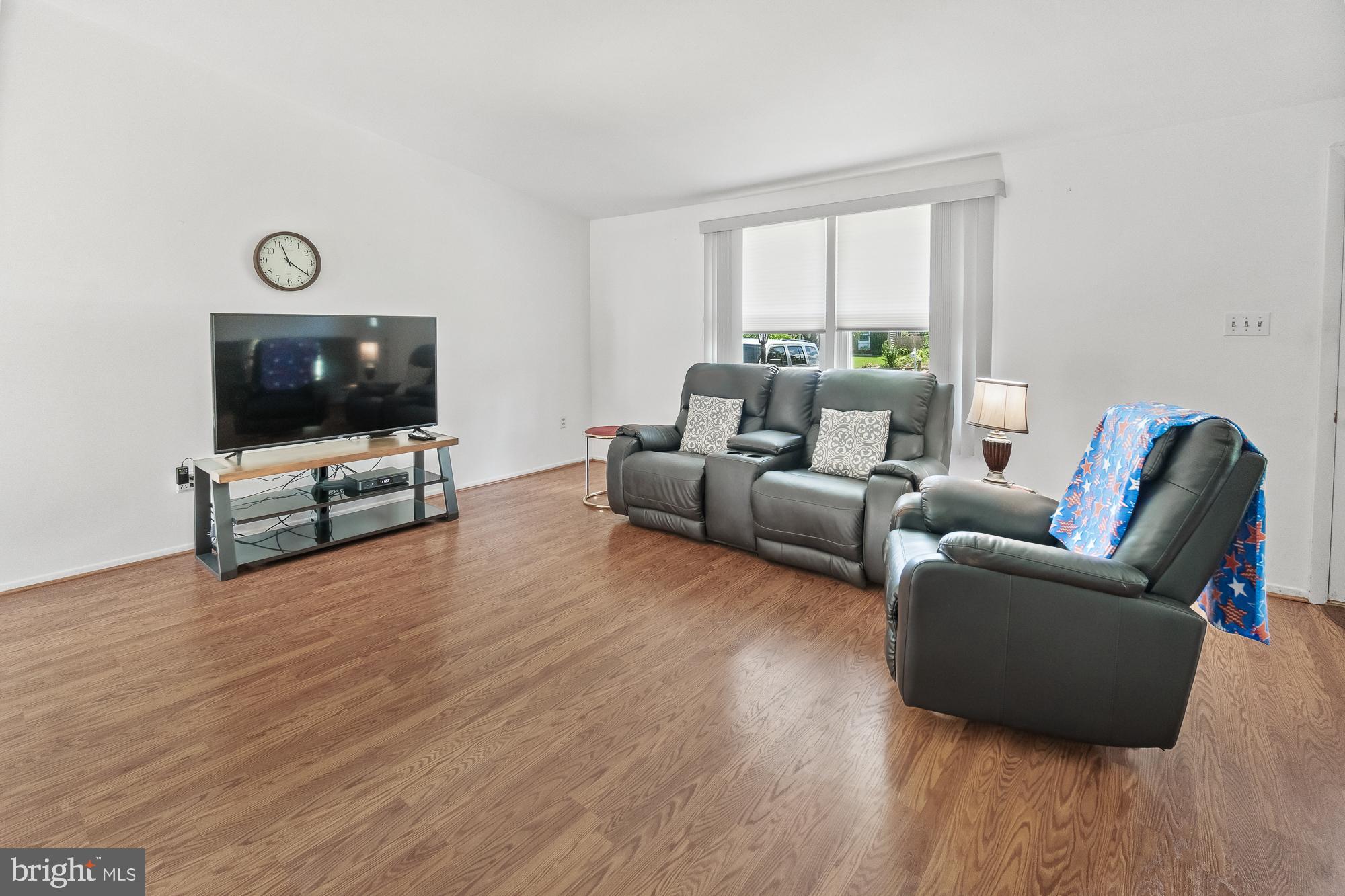 Living room with gray leather seating, wood-look floors, and a television.