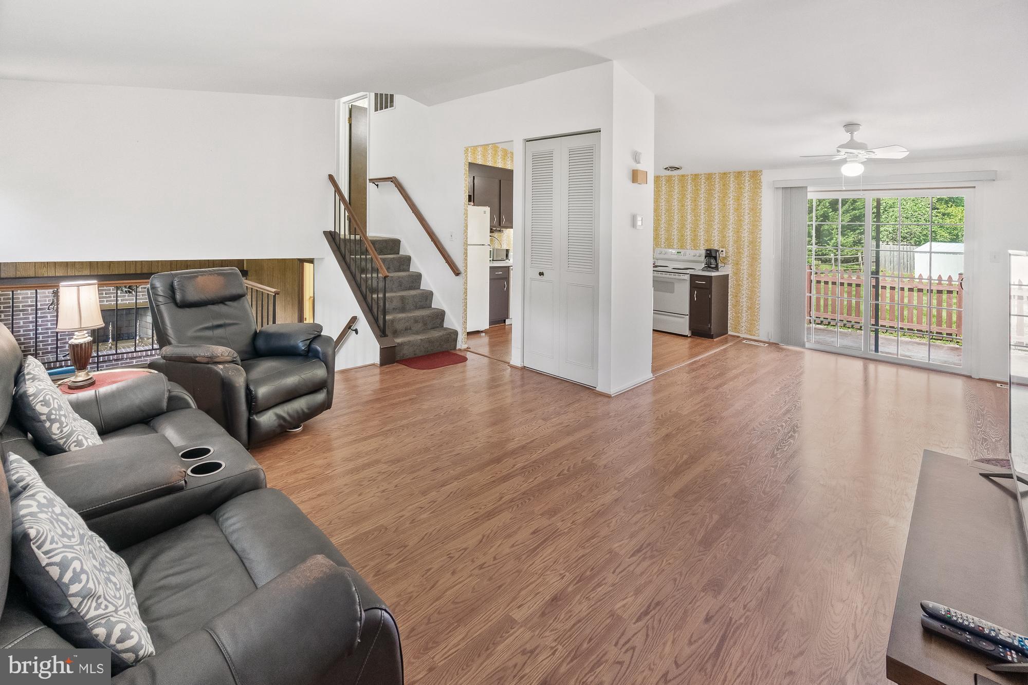Living room with wood floors, brick fireplace, carpeted stairs, and sliding glass doors to a deck.