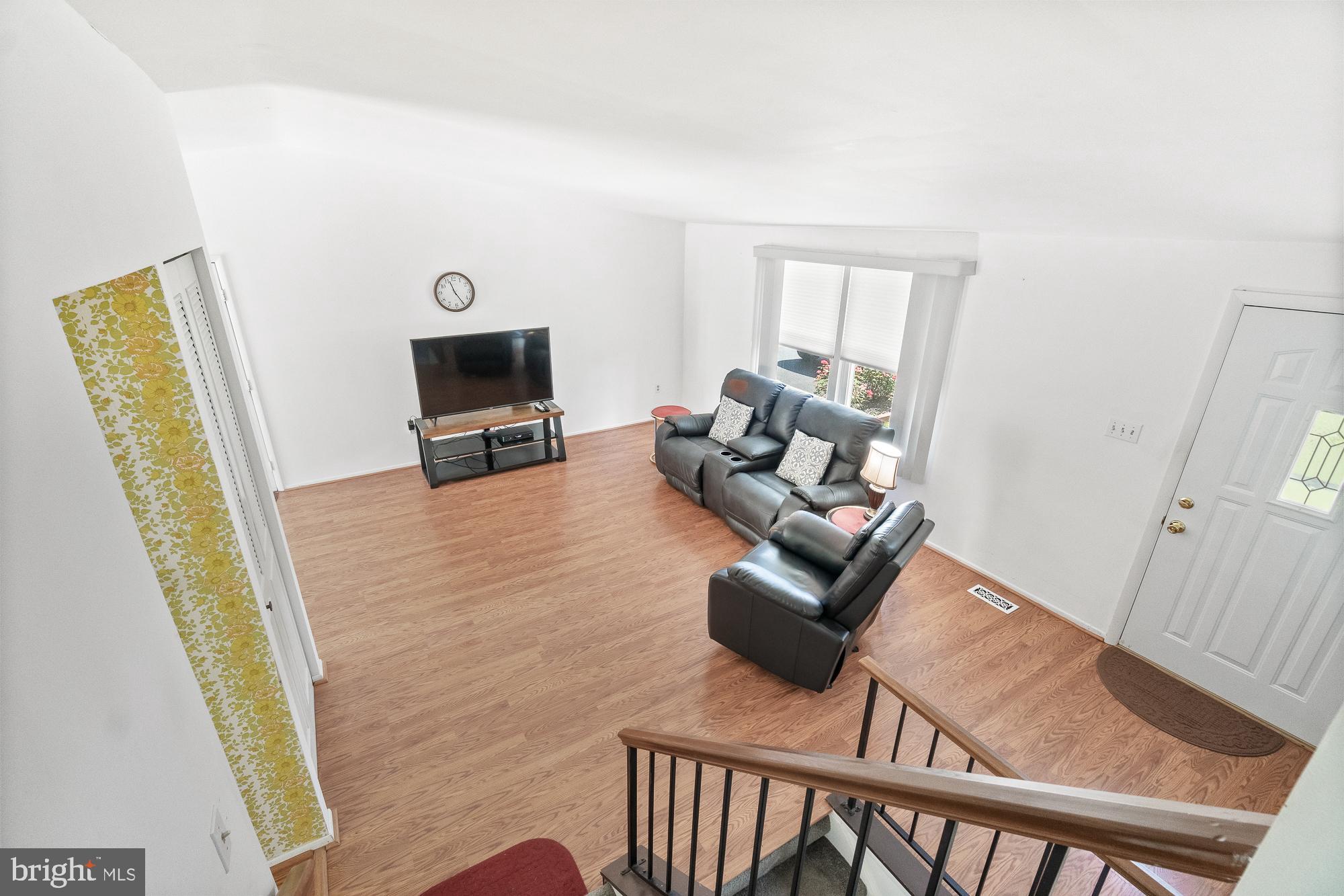 Furnished living room with gray leather recliners, wood-look flooring, and a television.