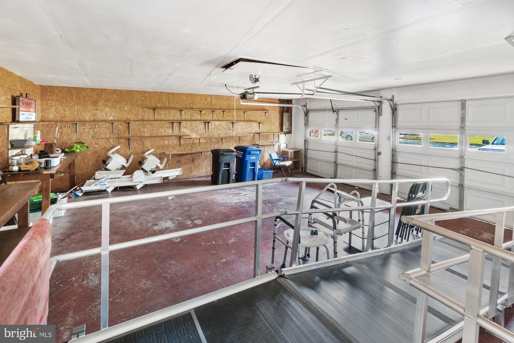 Garage with two overhead doors, wall shelving, and sturdy access rails surrounding a raised platform.
