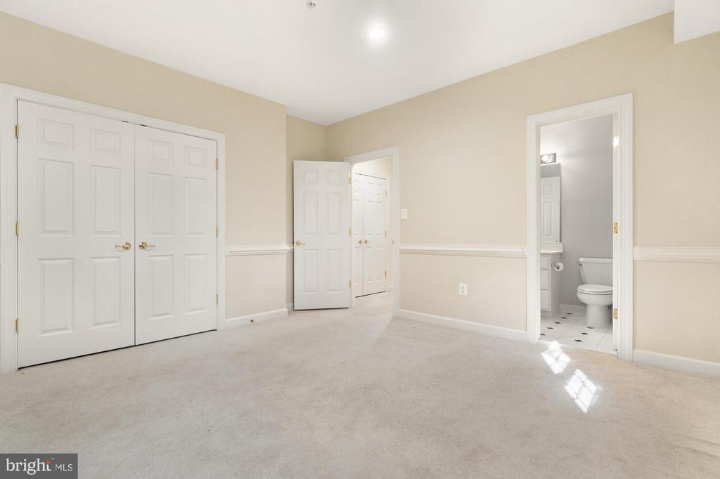 Empty carpeted bedroom with double closet doors and an open doorway to a bathroom.