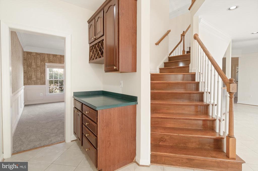 Wood staircase beside a built-in cabinet with a green countertop and doorway to a carpeted room.