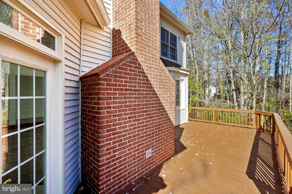 Rear deck beside a red brick chimney, with wooded surroundings.