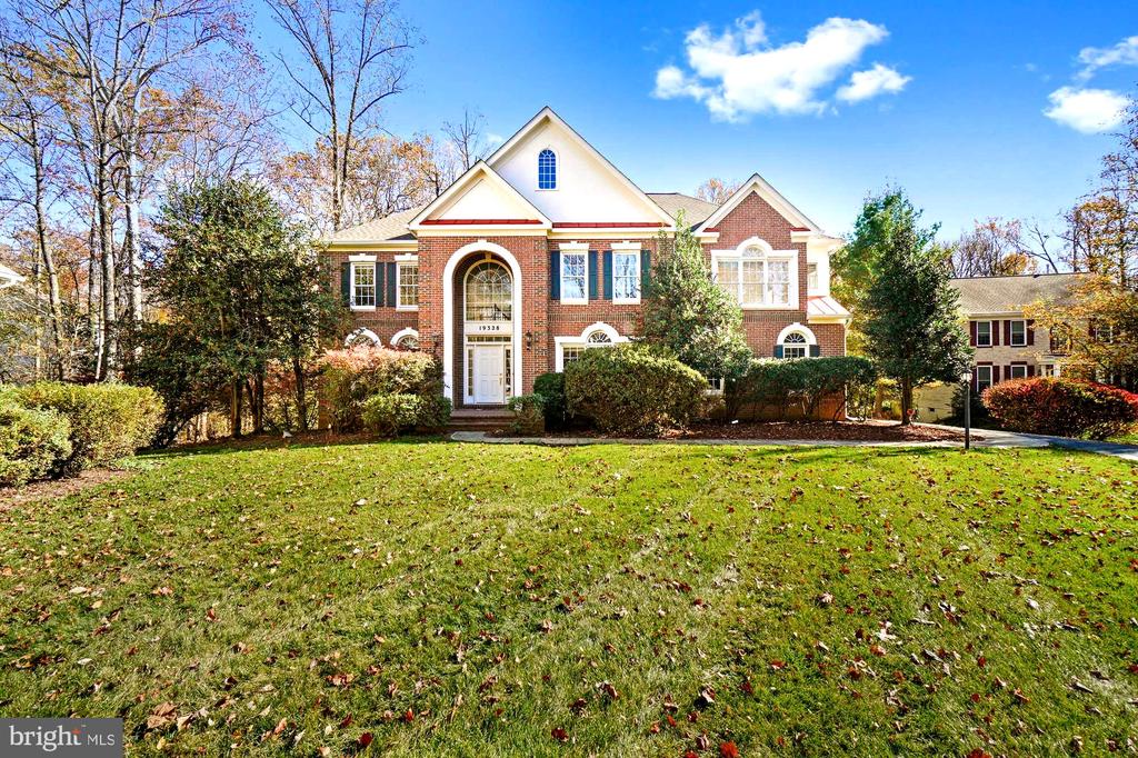 Red brick home with an arched entry, white trim, and a broad front lawn.